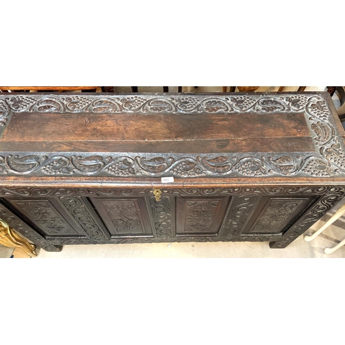 903 - A 19th century carved oak chest with four panel front, scrolling carvings of leaf and vine to top, L... 