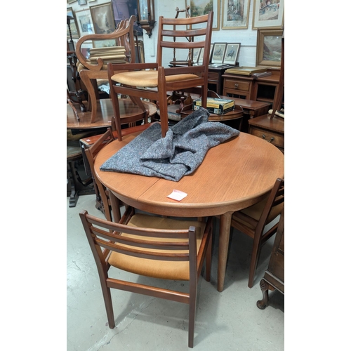 1011 - A 1960's circular extending teak dining table and four low ladder back chairs.