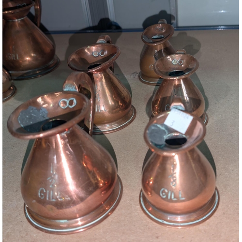 3 - 6 copper jugs, 1/8th gill to 1/2 gill, each with pewter stamps to the rim.