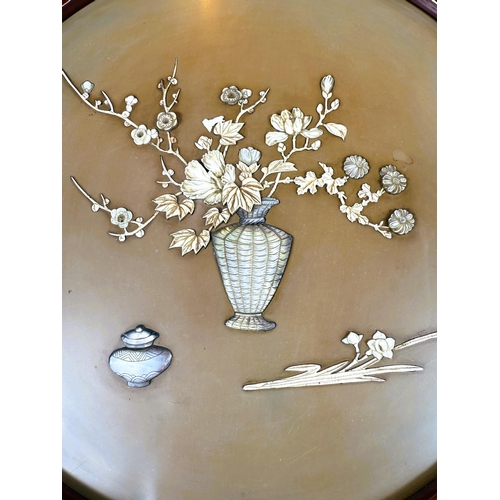 422 - A circular Japanese/Chinese relief picture depicting a vase of flowers in mother of pearl etc, in re... 