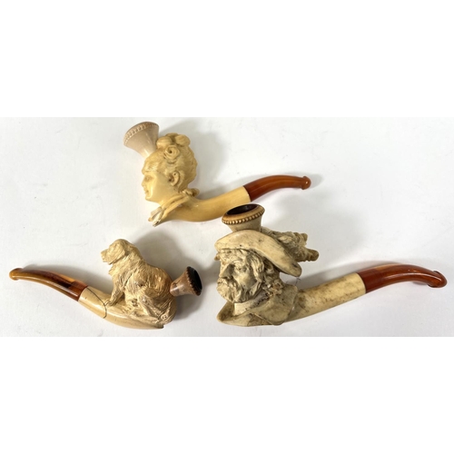 46 - 3 cased amber and Meerschaum pipes depicting seated dog (small crack); a woman's head;  a caval... 