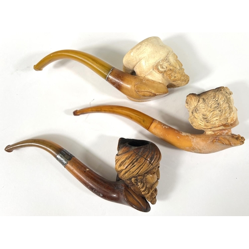 54 - 3 amber and Meerschaum pipes, 2 cased, depicting:- Turk's head with turban; bearded man's head and a... 