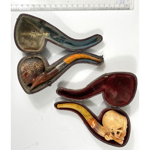 56 - 2 cased amber and Meerschaum pipes depicting skull and crossbones and black man's head.