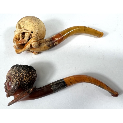 56 - 2 cased amber and Meerschaum pipes depicting skull and crossbones and black man's head.