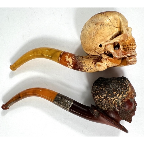 56 - 2 cased amber and Meerschaum pipes depicting skull and crossbones and black man's head.