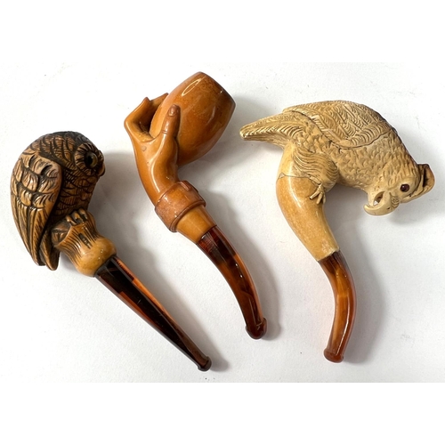 62 - 3 small amber and Meerschaum pipes, including hand holding egg (cracked); perching parrot (cased wit... 