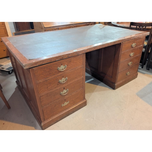 1008 - A large early 20th century oak twin pedestal office desk with inset leather effect top, 8 pedestal d... 