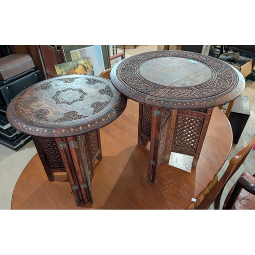 1010 - A pair of circular brass inlaid hardwood Eastern oil tables on folding bases