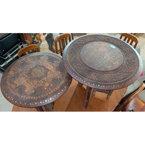 1010 - A pair of circular brass inlaid hardwood Eastern oil tables on folding bases