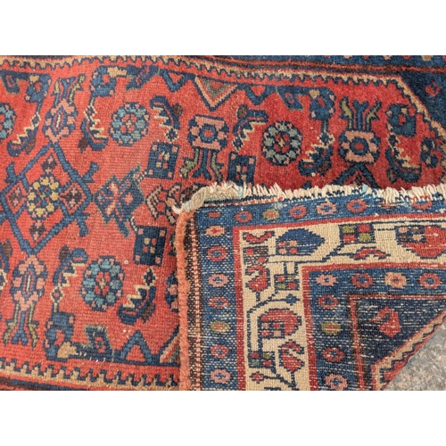 1015 - A mid 20th century red ground hand knotted Persian rug with Herati motifs to the field, 117 x 77cm.