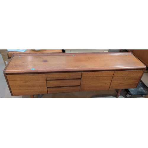 985 - A mid-20th Century teak White and Newton long low side board with carved lip to the back with drawer... 