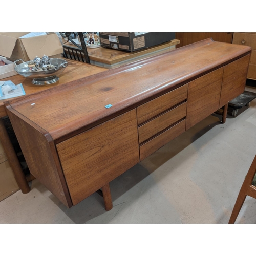 985 - A mid-20th Century teak White and Newton long low side board with carved lip to the back with drawer... 