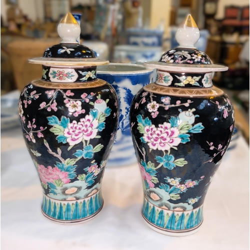 402A - A 19th century Chinese pair of Famille Noir lidded vases with polychrome decoration of birds and flo... 