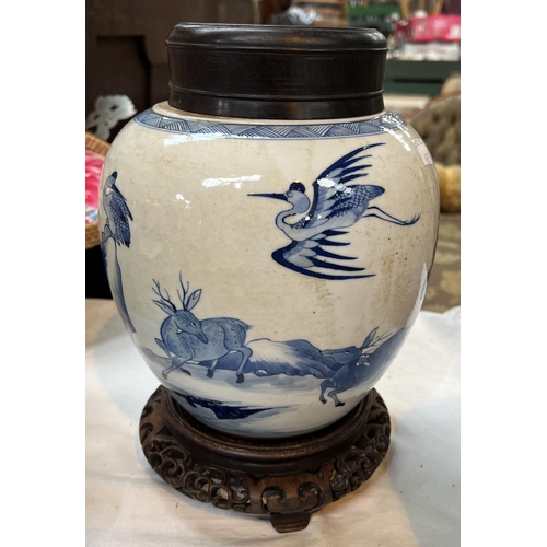 433A - A Chinese blue and white ginger jar on associated stand with wooden decorated with trees and animals... 