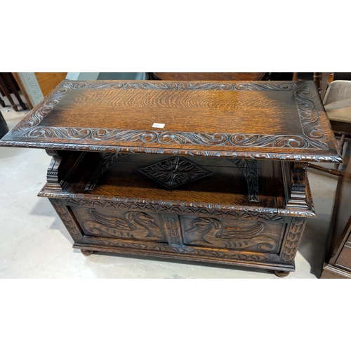 847 - A carved oak monks bench with hinged storage and sphynx supports.