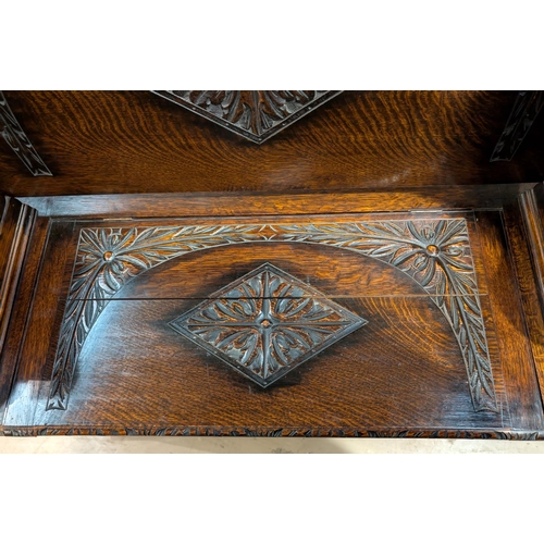 847 - A carved oak monks bench with hinged storage and sphynx supports.