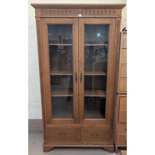 852 - A full height modern light oak display cabinet enclosed by glazed doors with 2 drawers to base.