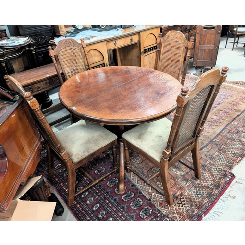 844 - An extending oak dining table with extra leaf and four splay pedestal feet below with four high back... 