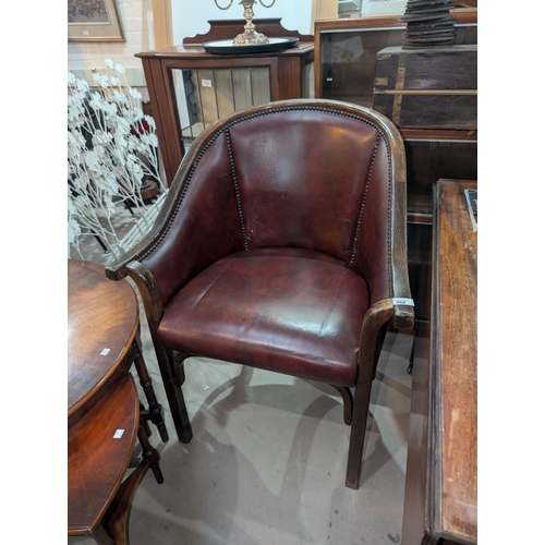 862 - An early 20th Century maroon leather library tub chair with studded decoration.