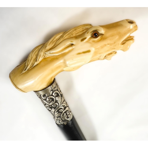 11 - A 19th Century ebonised walking stick with carved ivory handle of two horses' heads, 92cms.