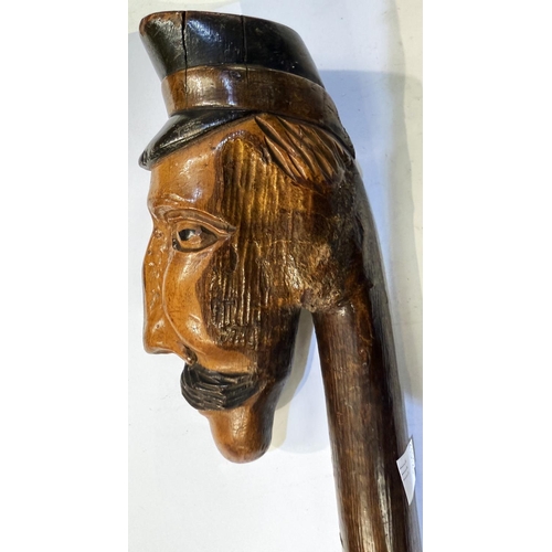 111 - An early 20th Century continental stick with carved head finial, 109cm, and another with ape finial,... 