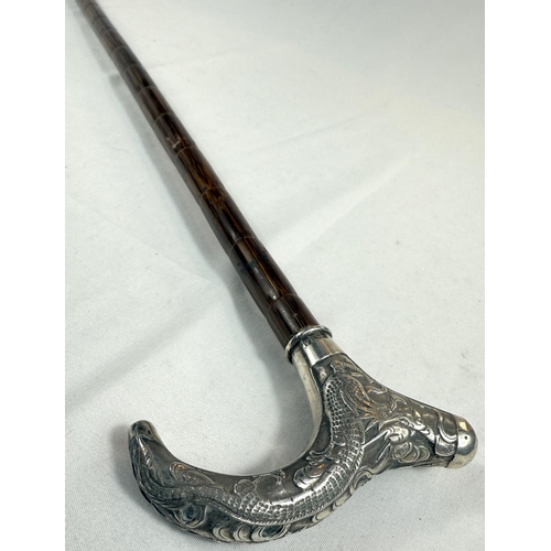 246 - A Chinese lady's walking cane with silver handle decorated with a dragon, 85cm.