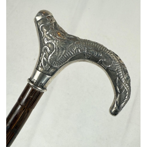 246 - A Chinese lady's walking cane with silver handle decorated with a dragon, 85cm.