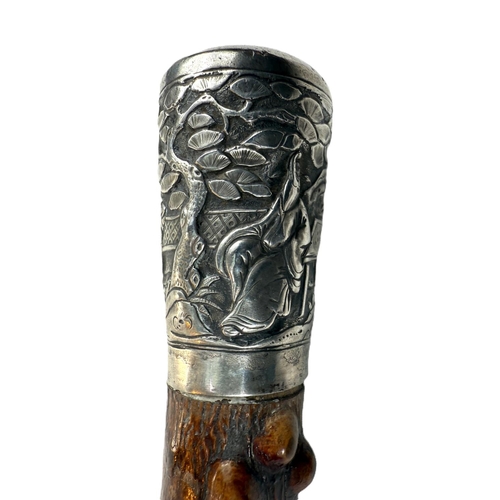 249 - A Chinese walking stick, the shaft with knobbly bark finish and having silver finial decorated in re... 