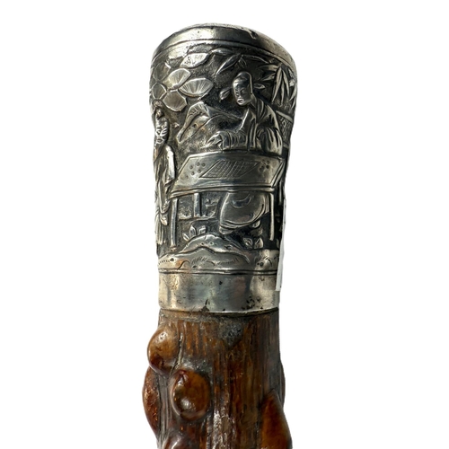 249 - A Chinese walking stick, the shaft with knobbly bark finish and having silver finial decorated in re... 