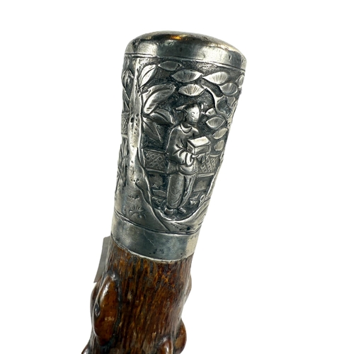 249 - A Chinese walking stick, the shaft with knobbly bark finish and having silver finial decorated in re... 