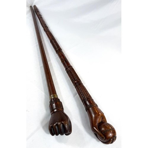 65 - A vintage carved hardwood stick of Asian origin, the finial with hand clasping a cricket ball, 91cm,... 