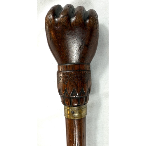 65 - A vintage carved hardwood stick of Asian origin, the finial with hand clasping a cricket ball, 91cm,... 