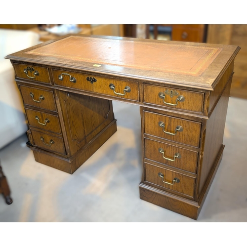 1011 - An oak pedestal writing desk with three frieze drawers and a pedestal with leather writing surface.