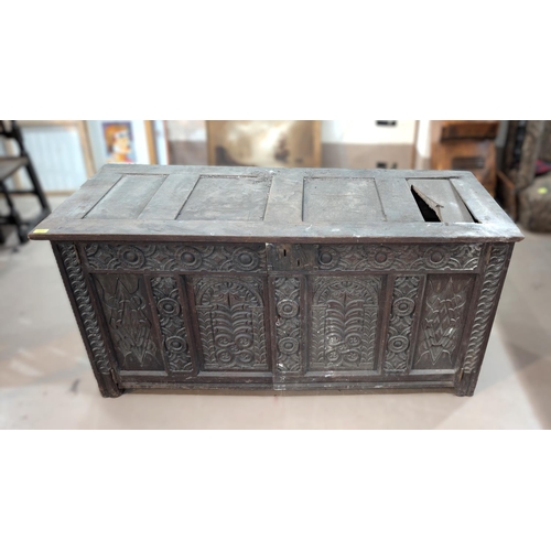 1023 - An 18th century oak framed and panelled blanket box with extensive carved decoration enclosed by 2 d... 