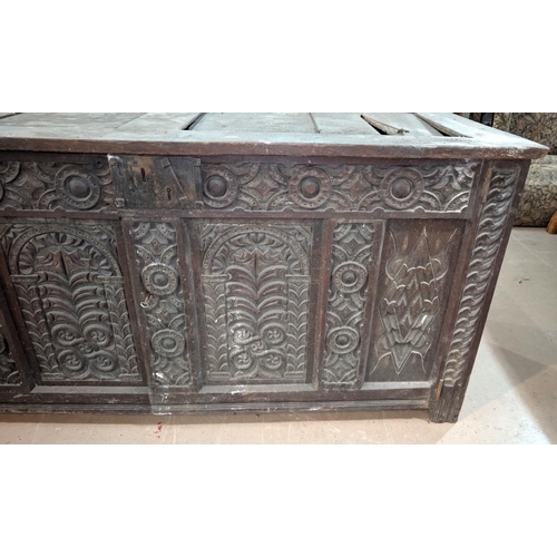 1023 - An 18th century oak framed and panelled blanket box with extensive carved decoration enclosed by 2 d... 