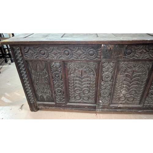 1023 - An 18th century oak framed and panelled blanket box with extensive carved decoration enclosed by 2 d... 