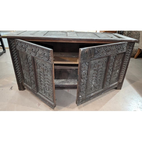 1023 - An 18th century oak framed and panelled blanket box with extensive carved decoration enclosed by 2 d... 