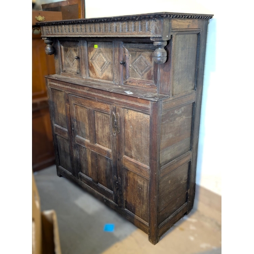 1057 - An 18th century oak court cupboard with twin diamond carved upper doors and framed and panelled sing... 