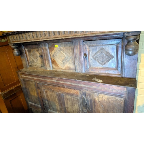 1057 - An 18th century oak court cupboard with twin diamond carved upper doors and framed and panelled sing... 