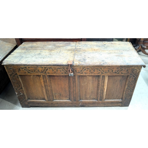 1060 - An early 19th century framed and panelled coffer with hinged plank top, scroll carved frieze, 4 pane... 