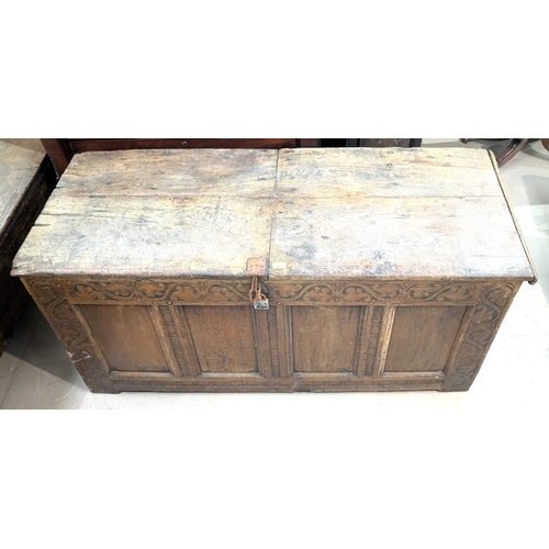 1060 - An early 19th century framed and panelled coffer with hinged plank top, scroll carved frieze, 4 pane... 