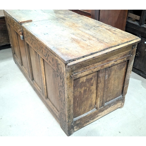 1060 - An early 19th century framed and panelled coffer with hinged plank top, scroll carved frieze, 4 pane... 