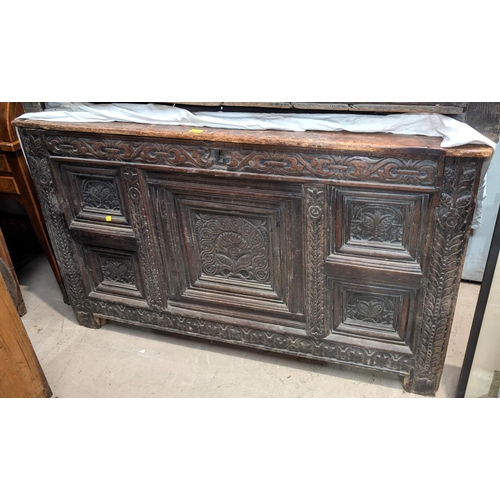 1071 - An extensively carved oak coffer with plank top.