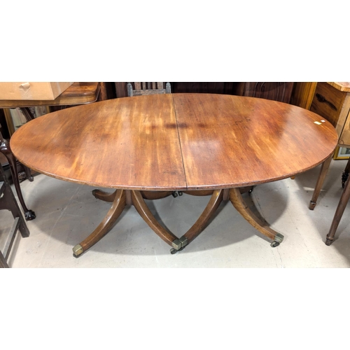 1077 - A 19th Century Regency-style twin pedestal mahogany dining table with one spare leaf, on turned colu... 