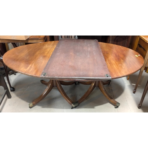 1077 - A 19th Century Regency-style twin pedestal mahogany dining table with one spare leaf, on turned colu... 