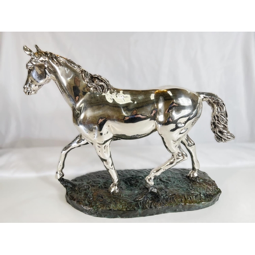 899 - A silvered metal sculpture of a horse on naturalistic bronzed base by 'D'Argenti', length 47cms.