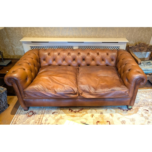 924 - A tan leather two seater scroll arm Chesterfield settee, length 183 cm.