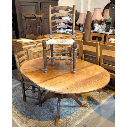 937 - A circular extending distressed oak extending dining table on central column and four splay feet, ex... 