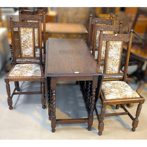 988 - An oak barley twist drop leaf dining table and a set of six carved oak dining chairs.