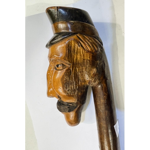 111 - An early 20th Century continental stick with carved head finial, 109cm, and another with ape finial,... 